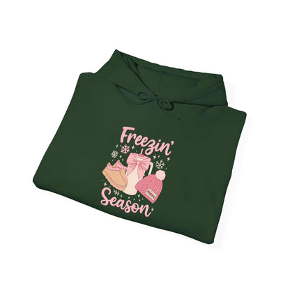 Green cozy hoodie with Freezin' Season graphic featuring winter boots, hat, and mittens illustration