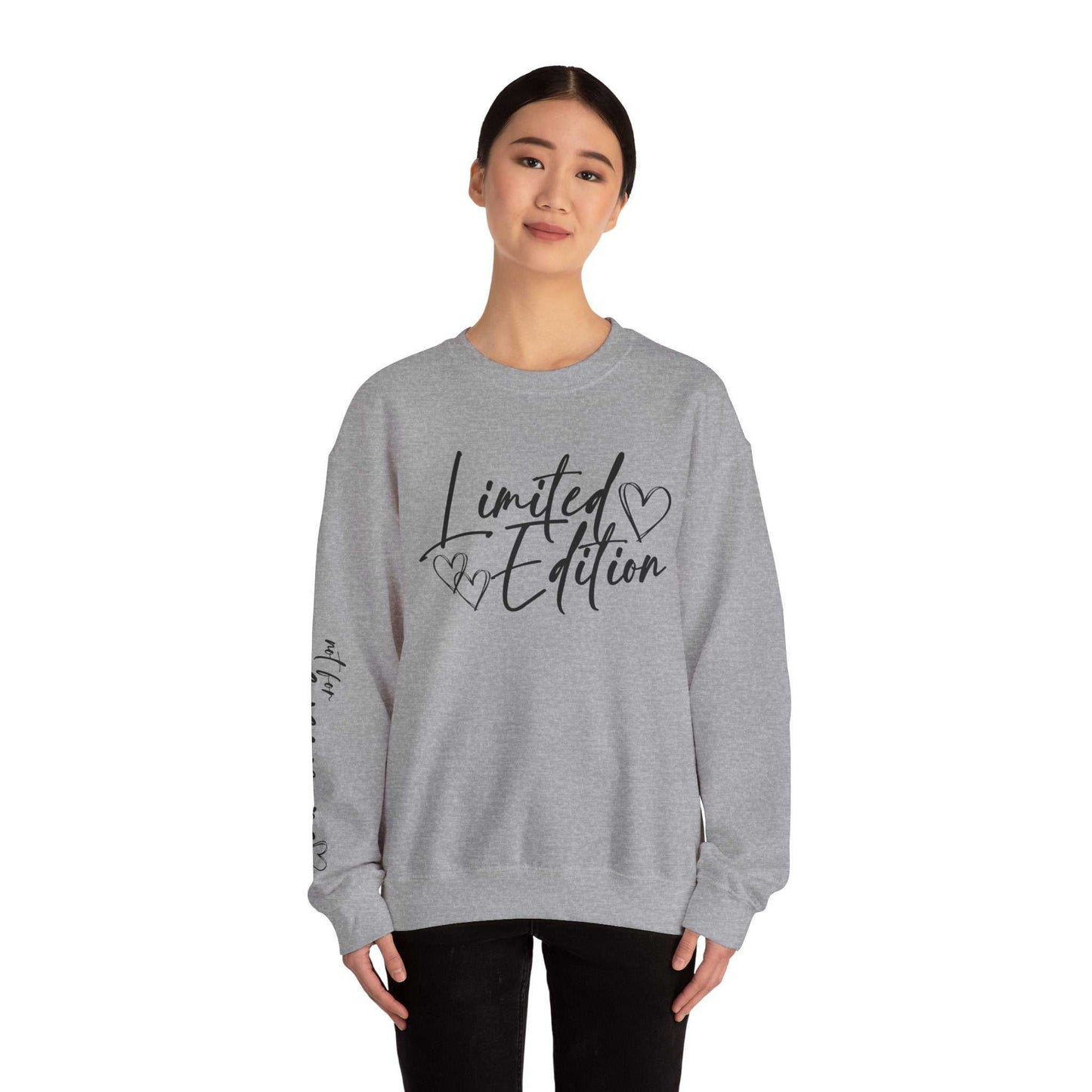 Woman wearing a grey Limited Edition Script Hearts Sweatshirt with black script and heart designs on chest and sleeve, casual crewneck style.