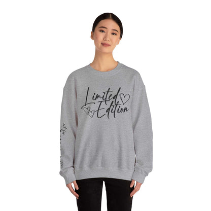 Woman wearing a grey Limited Edition Script Hearts Sweatshirt with black script and heart designs on chest and sleeve, casual crewneck style.