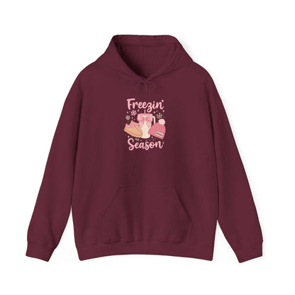 Cozy burgundy hoodie with Freezin' Season graphic featuring winter boots, hat, mittens, and warm design