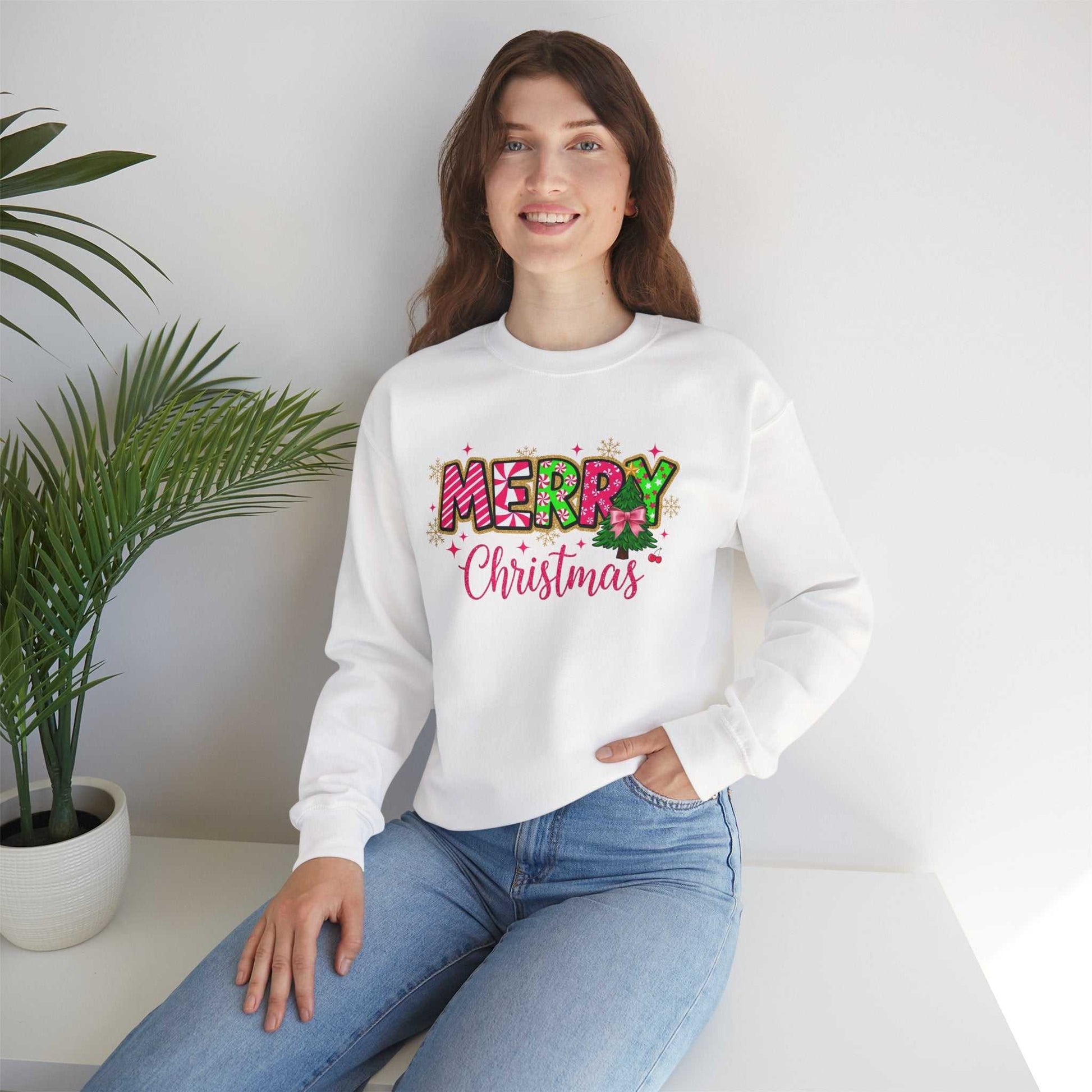 Woman wearing white crewneck sweatshirt with colorful Merry Christmas Candy Cane typography design sitting indoors