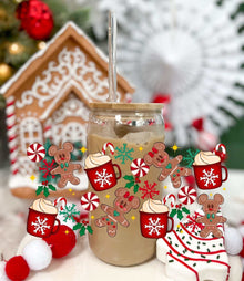 Hot Chocolate Ginger Bread glass can with acrylic lid and straw, decorated with festive gingerbread and peppermint designs in front of a gingerbread house.