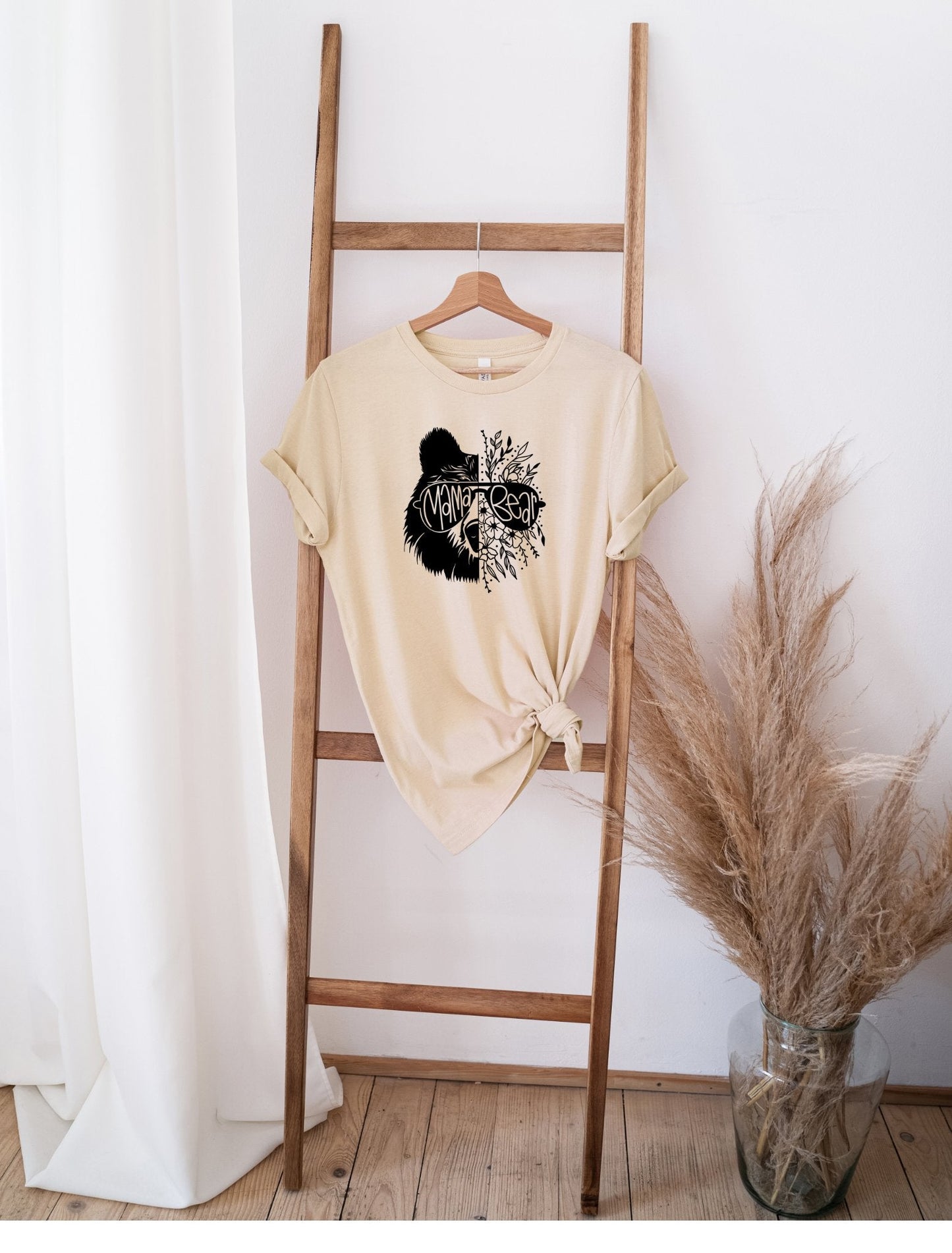 Mama Bear beige t-shirt with black bear graphic hanging on wooden ladder in minimalist room